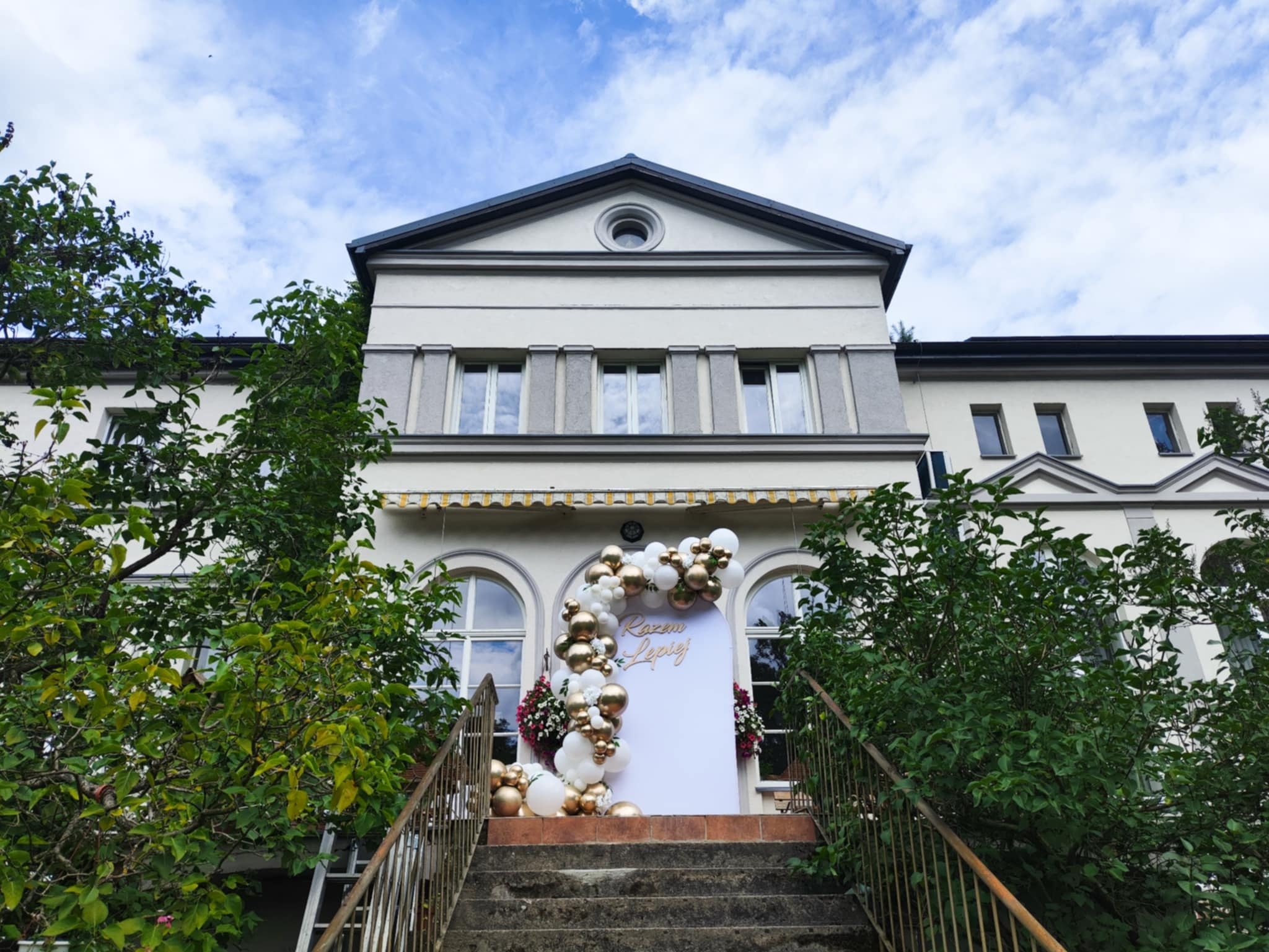 Ślubna dekoracja z panelem, kwiatowymi akcentami i strefą zdjęciową dopasowaną do eleganckiego przyjęcia